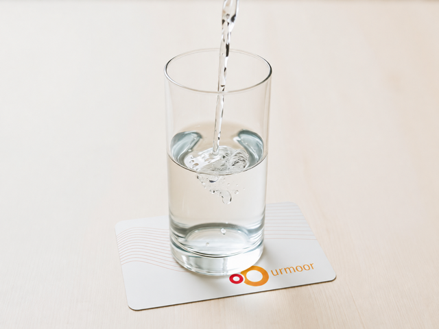 Wasser wird in ein Glas gegossen, das auf einer weißen urmoor Card steht